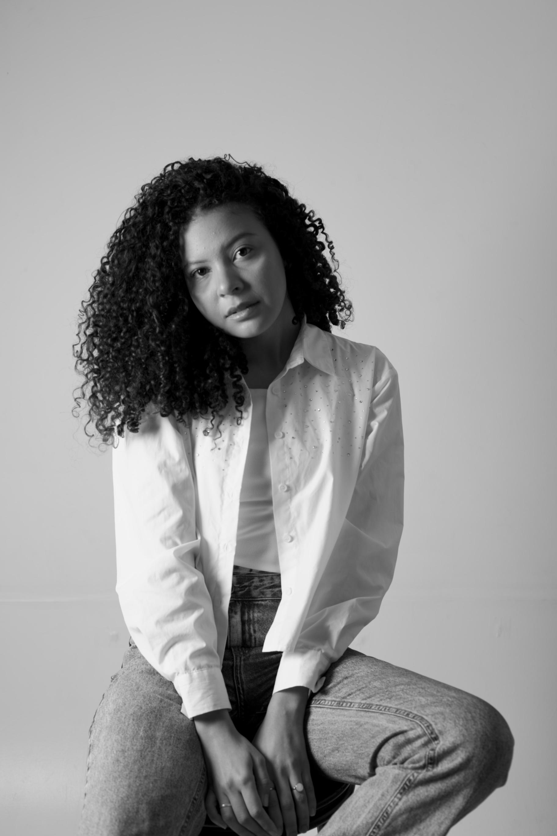 Retrato em preto e branco de mulher sentada com camisa branca